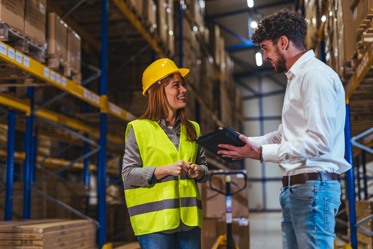 Warehouse supervisor and manager review inventory on a tablet