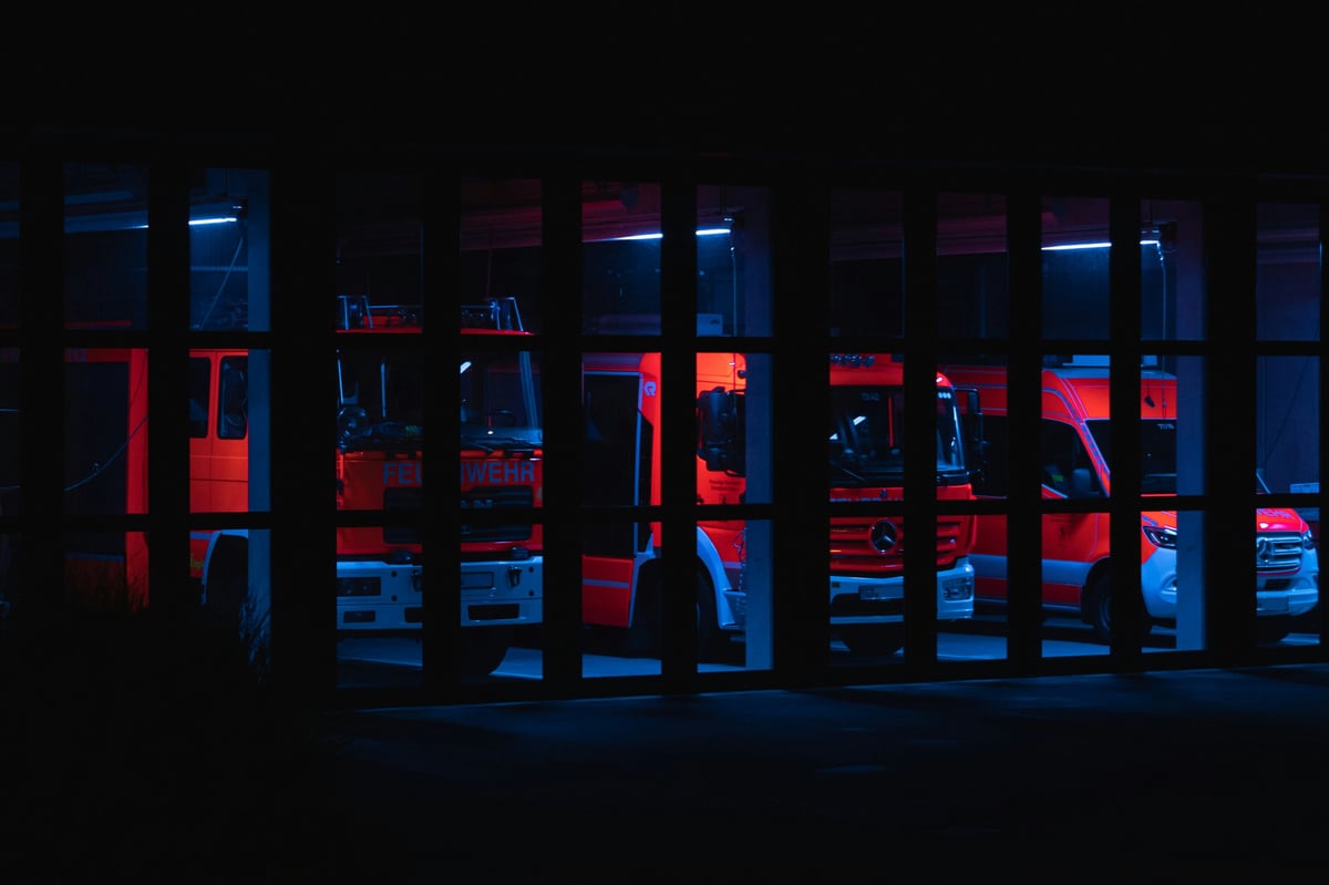 Storefront window at night with red and blue neon lighting displaying merchandise behind glass panels